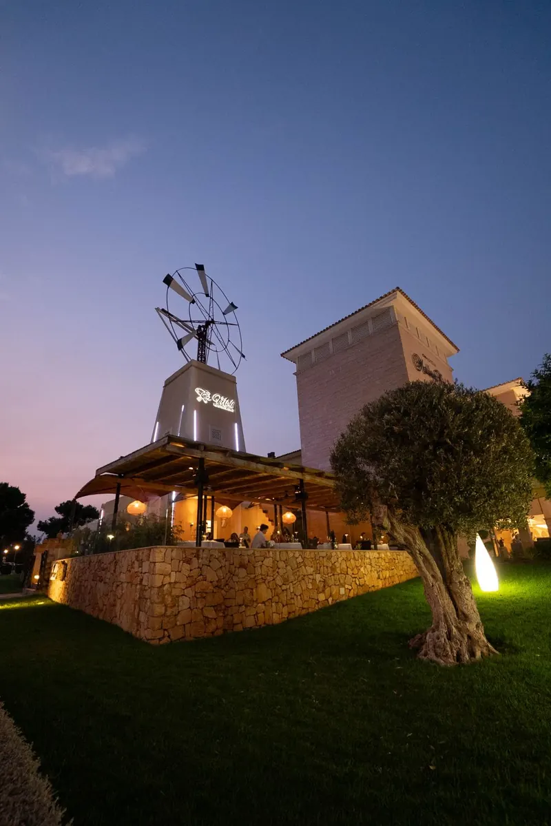El molino de Es Molí Restaurant iluminado al anochecer en Sa Coma