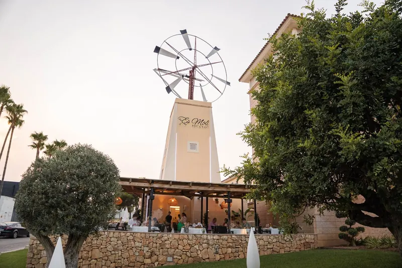 Fachada de Es Molí Restaurant con su molino y terraza en Sa Coma